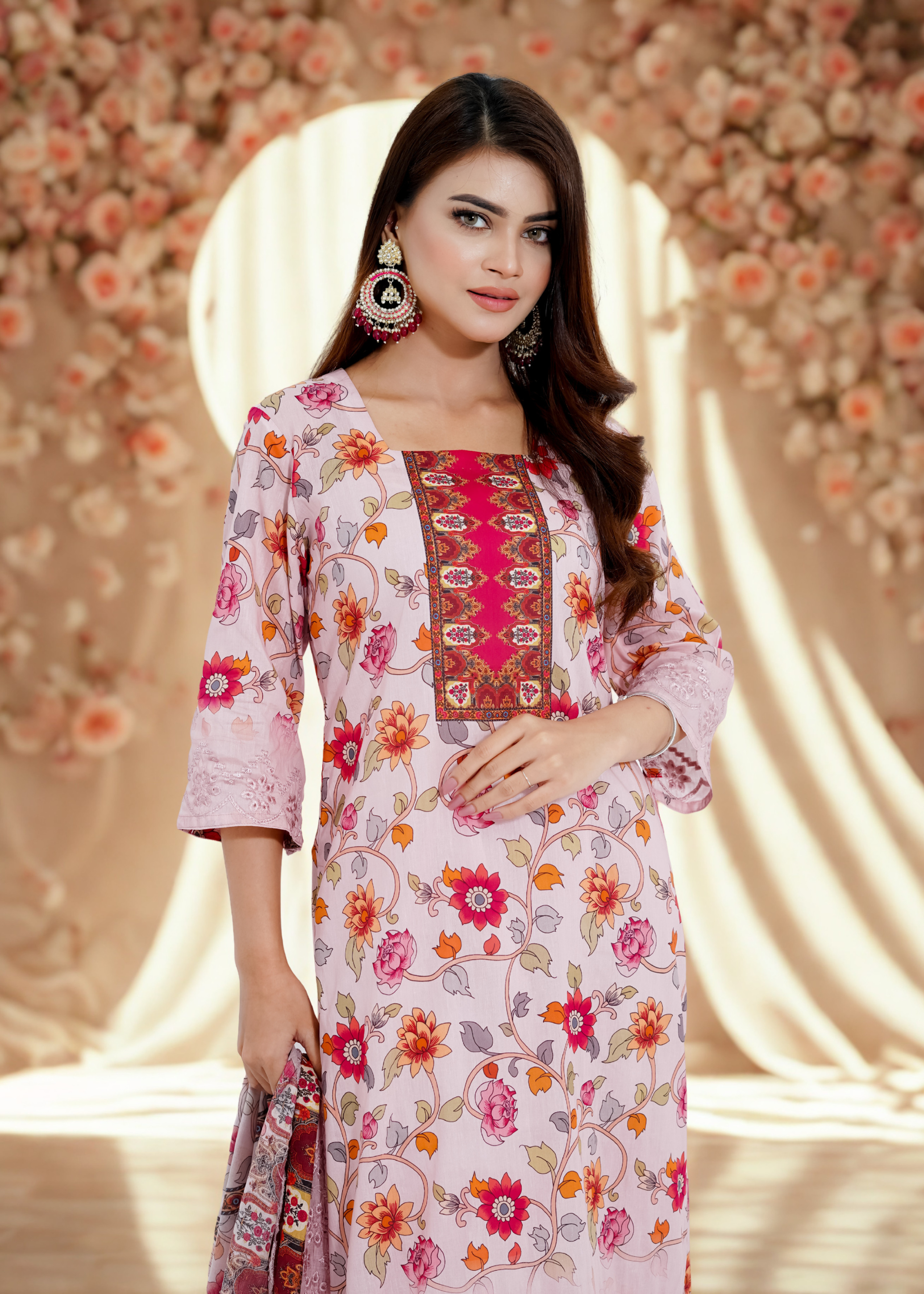 Woman wearing a floral dress with intricate patterns against a decorative background